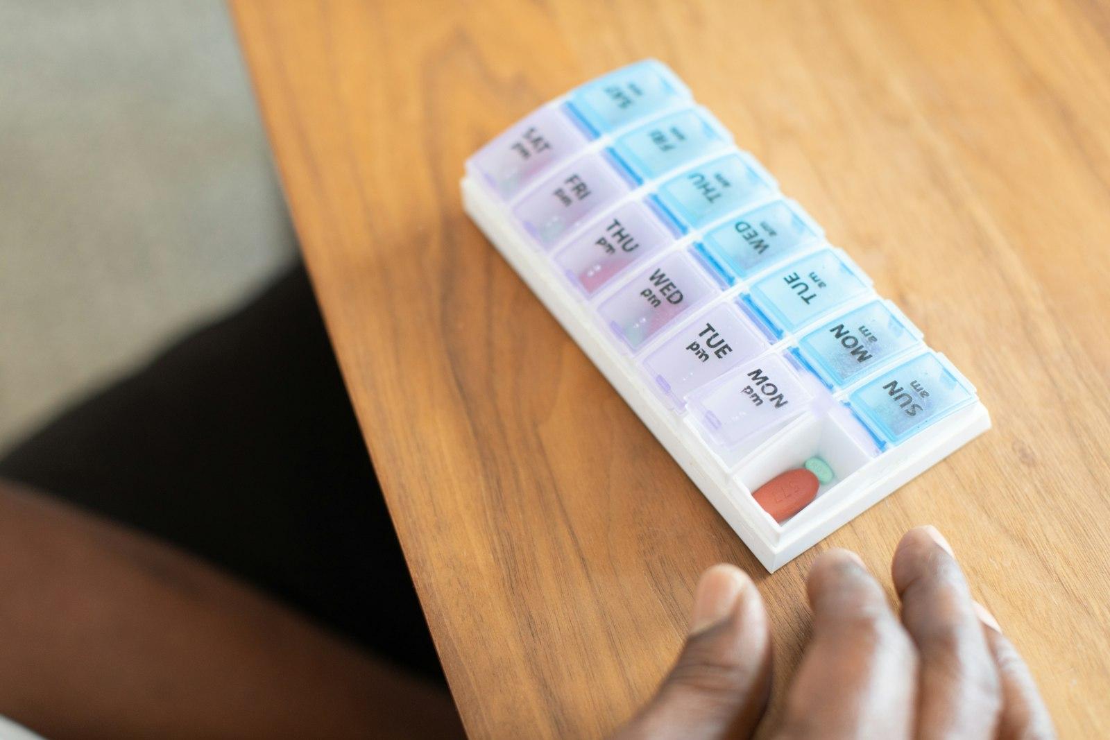 A weekly pill organizer resting on a warm wooden table