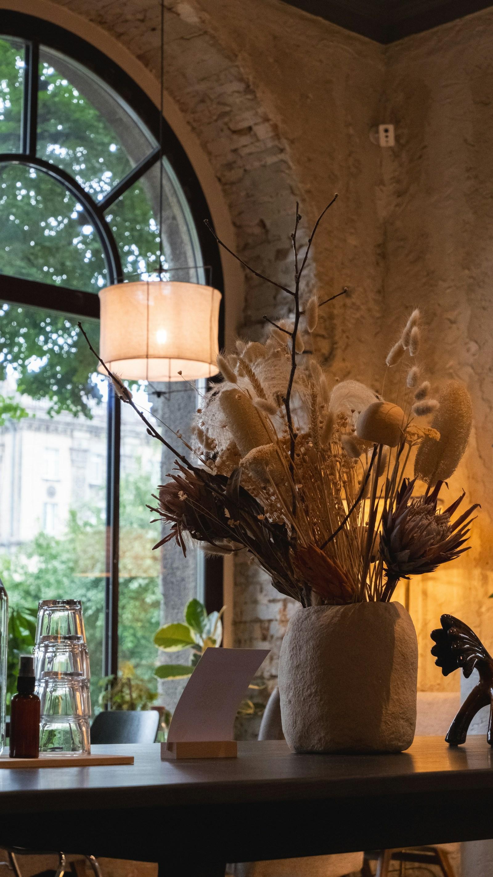 Dried flowers on a table beside a tall arched window